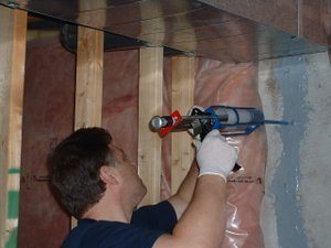 Technician injecting foundation crack with epoxy under low pressure