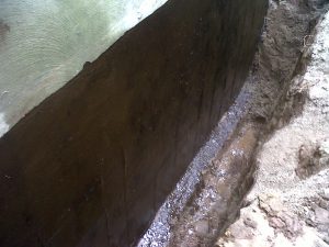 The waterproof rubber coating applied to exterior surface of a foundation wall prevents water from penetrating the wall