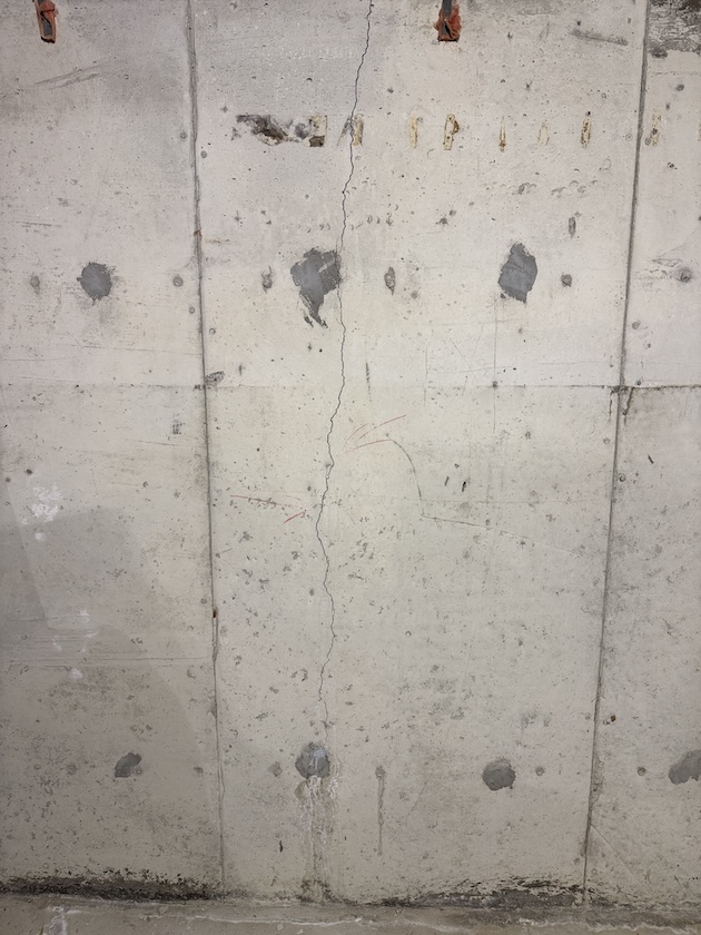Section of poured concrete foundation wall with patched tie-rod holes
