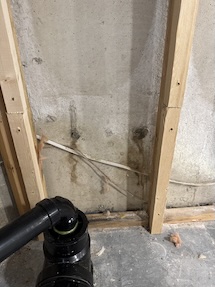 Pair of leaking tie-rods with visible mud staining on the foundation wall