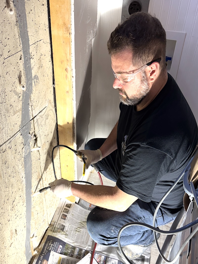 Technician injecting polyurethane resin into a foundation wall crack