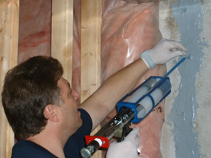 Low-pressure epoxy crack injection being performed on a poured concrete foundation wall