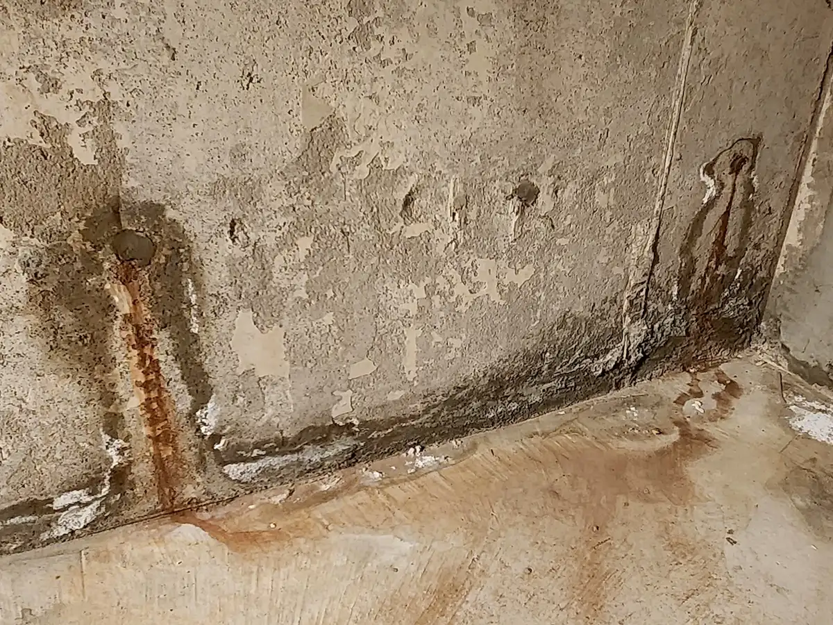 Two leaking tie rod holes with heavy water staining on a poured concrete foundation wall in Oakville