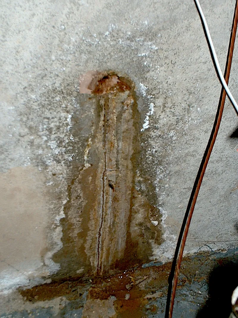 Tie rod hole with mud and mineral staining caused by repeated water seepage