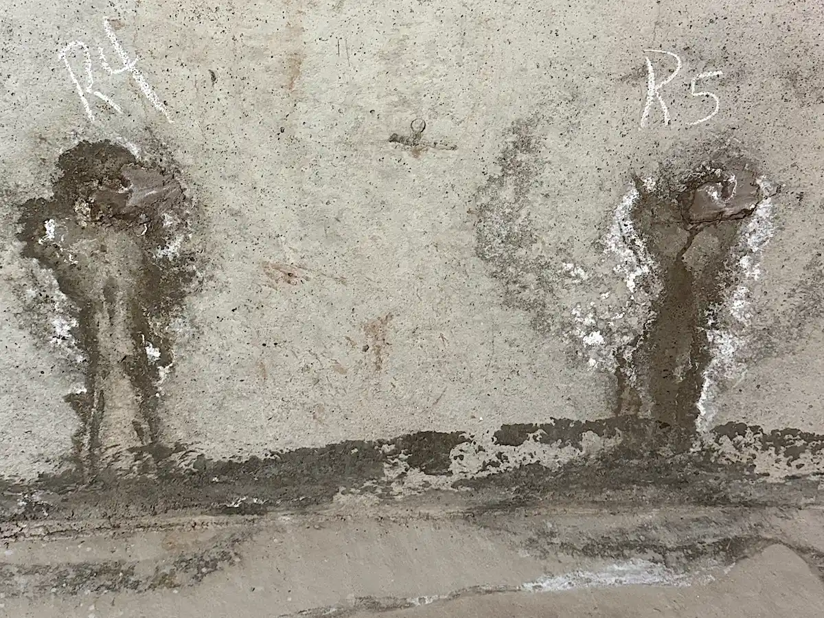 Tie rod holes showing evidence of past water leakage and staining on a concrete foundation wall
